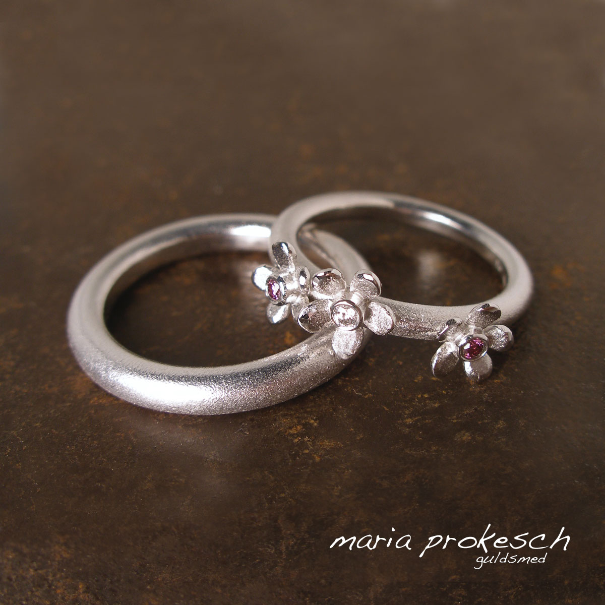 Enkle vielsesringe i 14 kt hvidguld. Hendes med tre fine blomster og behandlede lyserøde diamanter. Simpelt og elegant design.