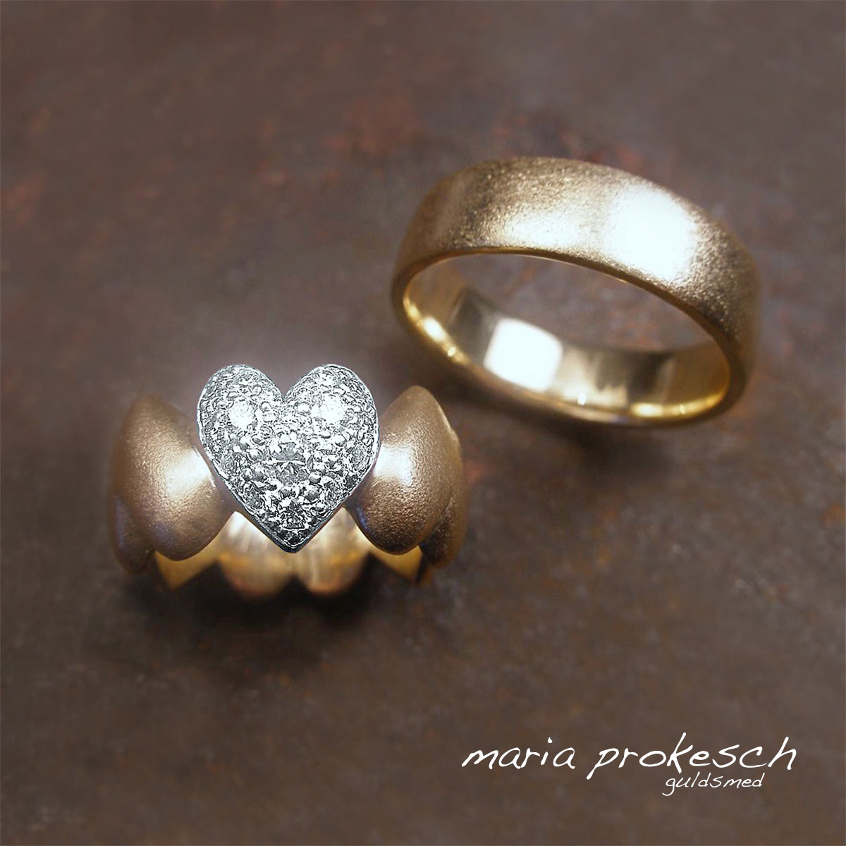 Eksklusive vielsesringe i guld 14 karat. Kvindens ring er en buttet hjertering med hjerter hele vejen rundt og et hjerte i 14 karat hvidguld, diamantbesat. Mandering helt enkel.