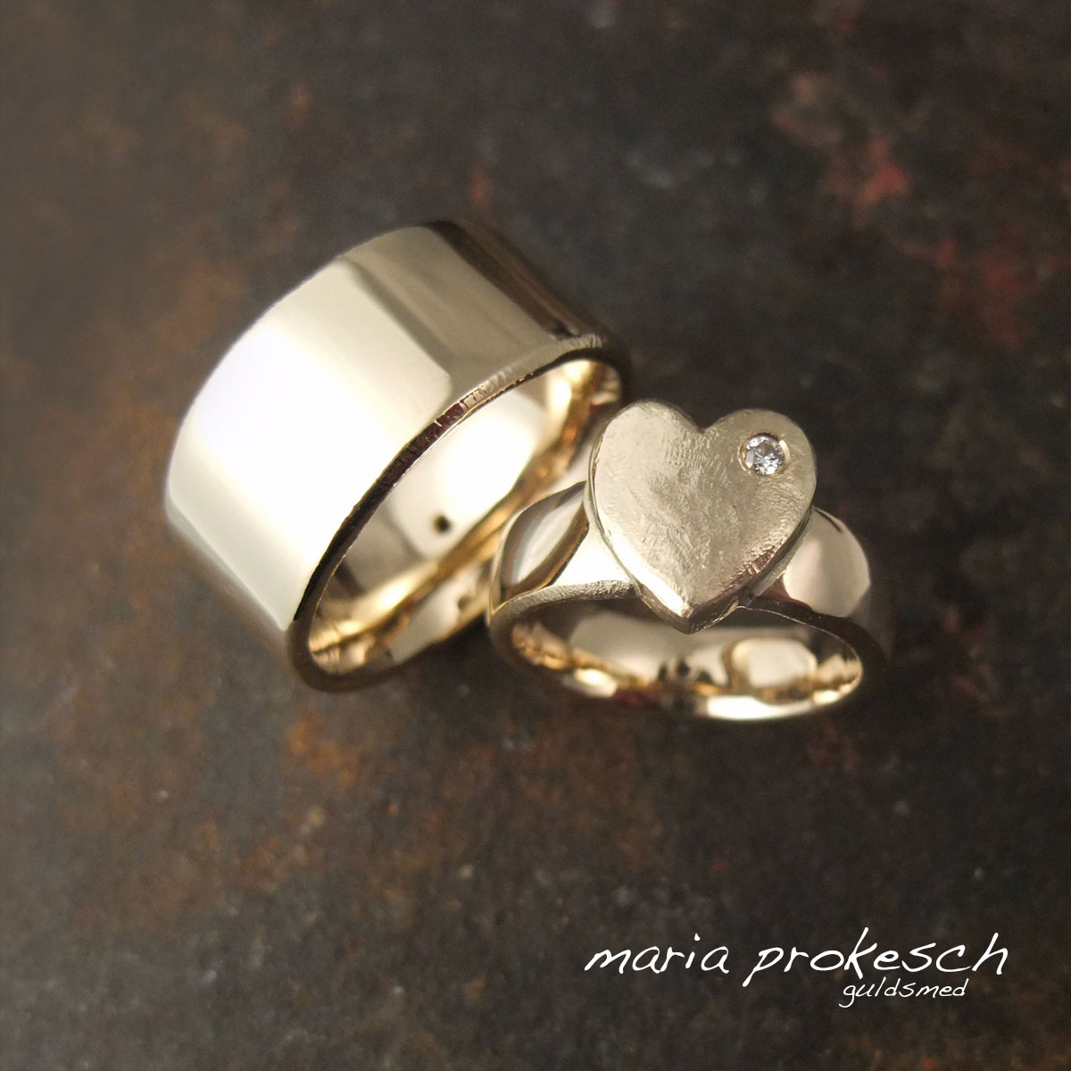 Et par glatte vielsesringe i 14 karat gult guld. Kvinde ring som hjertering med brillant (diamant). Begge har en kombination af blankt sammen med rå ujævne sider. Specielle og lækre håndlavet af guldsmeden