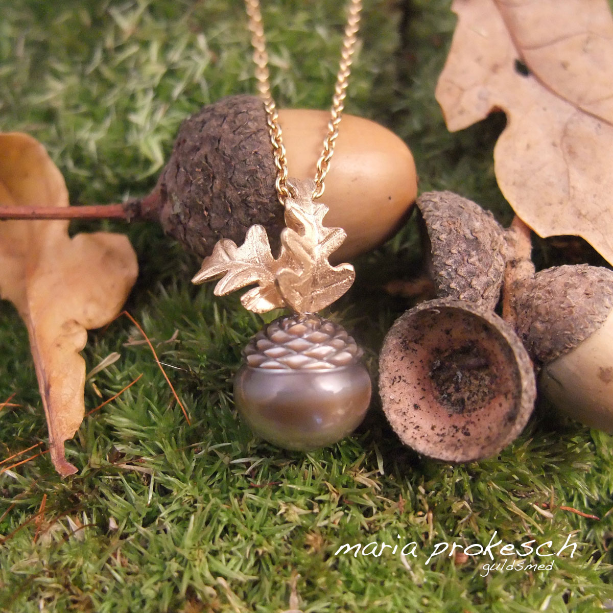Perlevedhæng i 18 karat med en graveret og facetteret Tahiti perle. Perlen ligner et agern som i naturen, ophænget i guld har håndlavede rustikke egeblade.